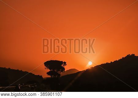 Picturesque Photo Of Vibrant Orange Sky Sunset On Highway With Cars Driving To Mountains With Sun Ab