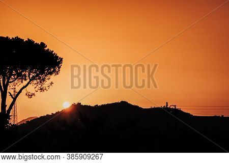Mountains, Cedar Crown Tree And Tower With High-voltage Wires Silhouettes On Beautiful Sunset With O