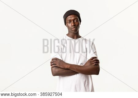 Portrait Of Unamused, Skeptical African-american Young Man In Beanie, Standing With Arms Crossed And