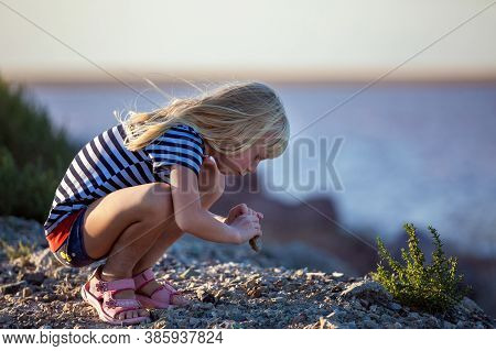 Little Girl Plays On Stones, She Is Looking For A Lost Toy.