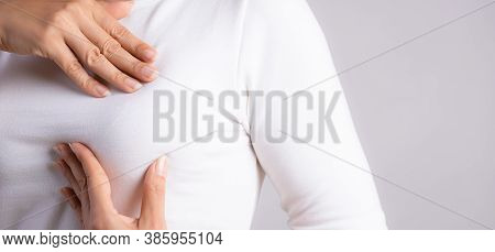 Woman Hand Checking Lumps On Her Breast For Signs Of Breast Cancer On Gray Background. Healthcare Co