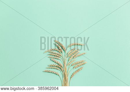 Bunch Of Compressed Stems With Ears. Golden Wheat On Green Paper Background. Wheat Close Up. Rich Ha