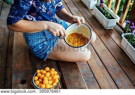 The Girl Prepares Jam From Yellow Plums. She Will Grind The Plums With A Fork.