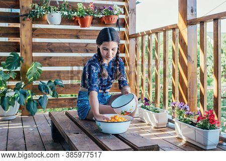 Girl Washes Yellow Fruits With Her Hands In A Bowl Of Water. Healthy Eating, Traditional Lifestyle.