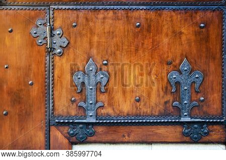 Plain Old Red Wooden Surface With Ancient Metal Decorated Hinges On The Door Of A Traditional Tuscan
