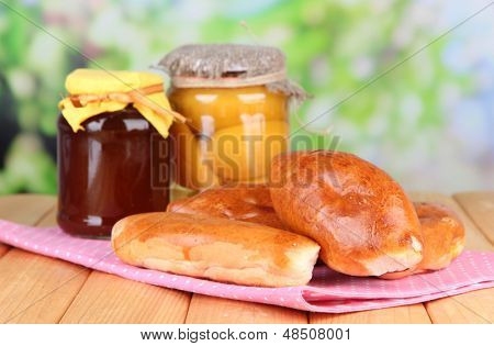 Empanadillas al horno frescos con mermelada de frutas, en la mesa de madera, sobre fondo brillante