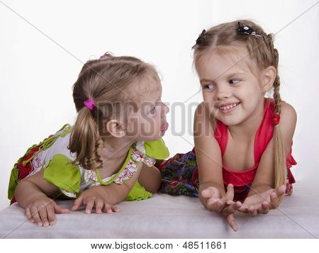Two girls lie, one tongue, the other smiles