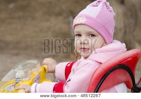 Two-year-old girl thoughtfully looks sitting on a bike