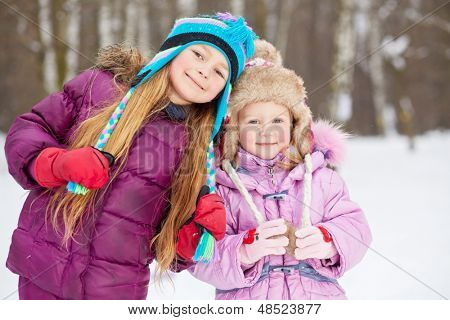 Twee lachende meisjes staan naast elkaar in winter park