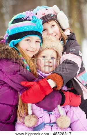 Drie meisjes staan elkaar omarmen in winter park