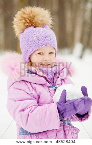Halve lengte portret van meisje in violet jas met bont kraag die in het bezit van grote sneeuwbal