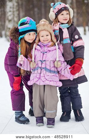 Drie meisjes - twee oudere en een jongere - staan samen in winter park