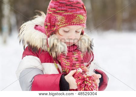 Klein meisje staat in winter park vogeltje witte kunstmatige opwarming van de aarde in haar handen