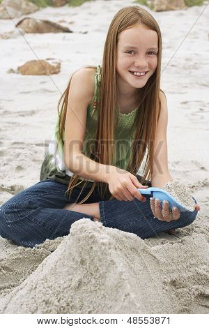 Porträt von glücklich niedliche kleine Mädchen machen Sandburg am Strand