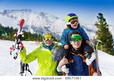 Parents and child on dad's shoulders in ski masks