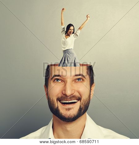 laughing young businessman with open head. young excited businesswoman dancing and raising hands up in the man's head. photo over grey background