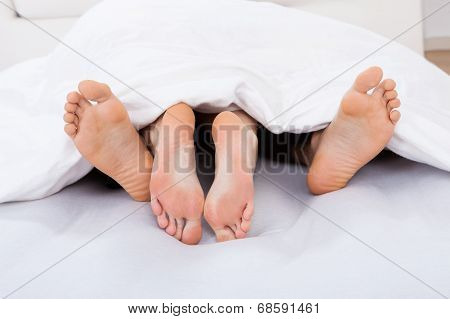 Low Section Of Intimate Couple Under Blanket