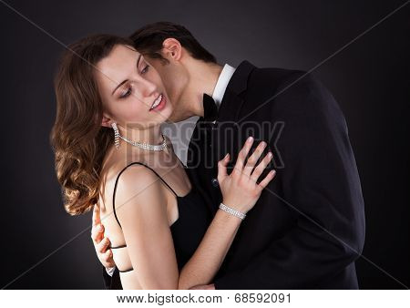Young Couple Embracing Over Black Background