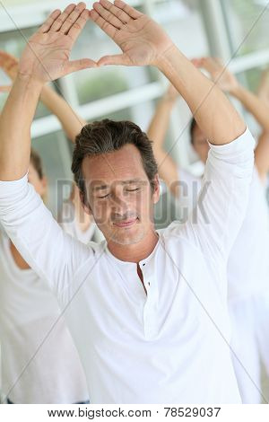 Mature man amongst group doing yoga exercises