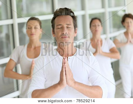 Mature man amongst group doing yoga exercises