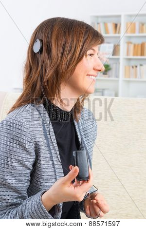Young, smiling woman showing cochlear implant