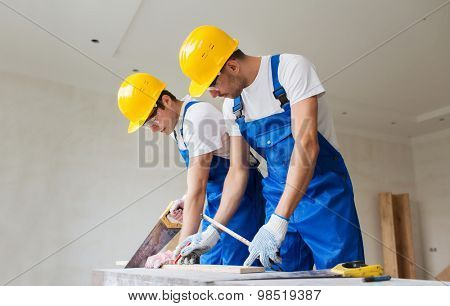 business, building, teamwork and people concept - builders working with arm-saws