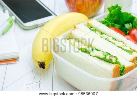 Lunch Box With Egg Salad Sandwiches, Fruits, Milk And Stationery