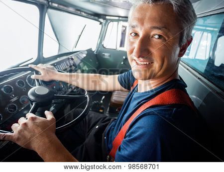Portrait of happy mature firefighter driving firetruck
