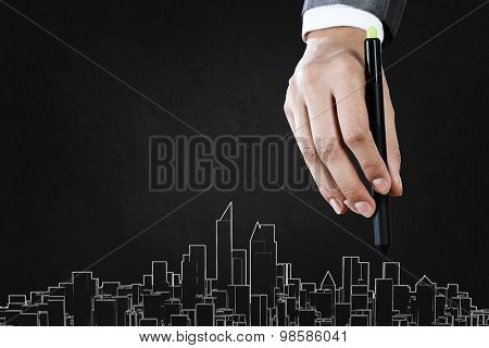 Close up of hand drawing urban city buildings