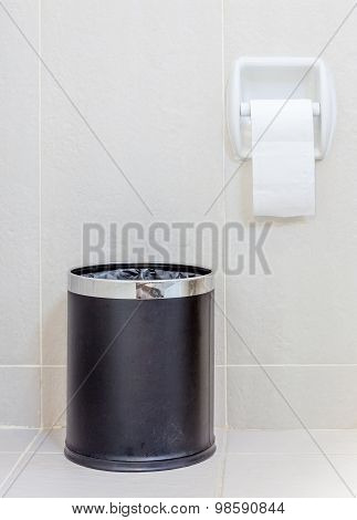 Toilet Paper And  Trashcan In White Hygeine Restroom.