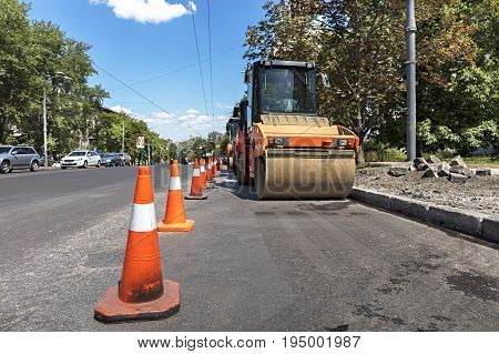 Orange road cones protect the working area for heavy vibrating compactors on a city street