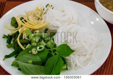 The close up of Thai fermented rice flour noodle (Khanom chin) with vegetable on white plate.