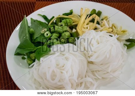 The close up of Thai fermented rice flour noodle (Khanom chin) with vegetable on white plate.