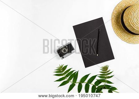 Straw hat with green leaves and old camera on white background, Summer background. Top view. Copy space. Still life. Flat lay