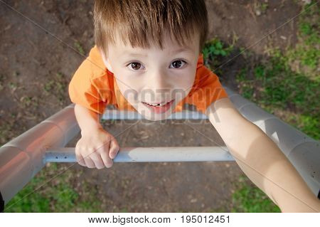 boy climbing stairs and playing outdoors on playground children activity. Child portrait from above. Active healthy childhood concept