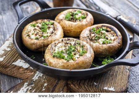 Traditional Italian Mushroom Caps stuffed with Feta as close-up in a rustic frying pan
