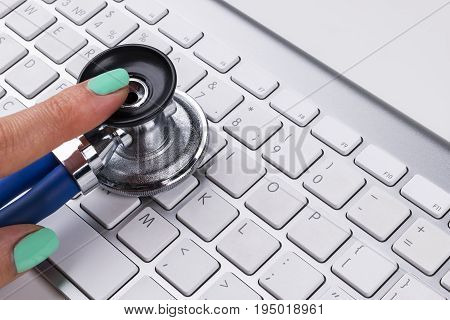 technician female (woman) hand using stethoscope for examines computer keyboard computer service concept computer and internet maintenance checking the health of laptop computer