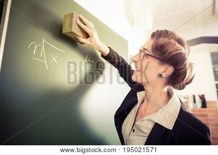 Math Teacher or docent cleaning the chalk of the board or  chalkboard or blackboard after the math lesson in school class