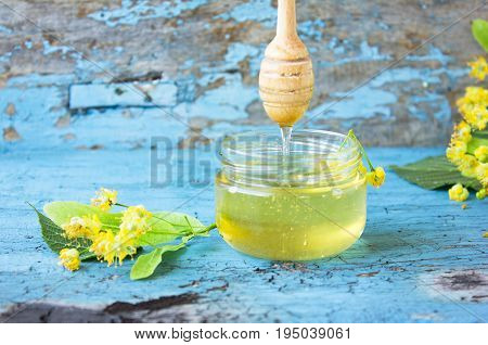 linden honey in glass jar on a blue background with a linden flowers and linden honey. Fresh linden