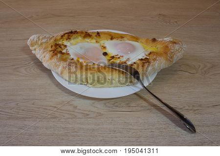 Khachapuri on ajarski - recipe of Georgian cuisine. Adjarian Georgian national dish Khachapuri bread with cheese and egg on a plate in a cafe