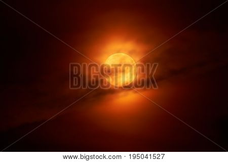 The moon appears in the night behind a cloud.