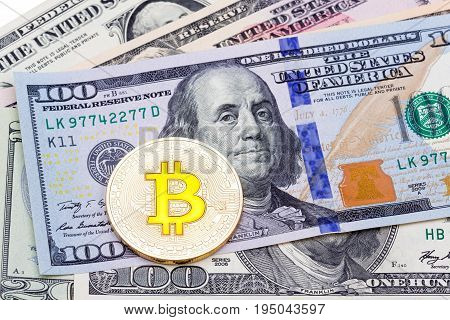 Closeup of golden yellow bitcoin on hundred dollars banknote, macro shot. High resolution photo.
