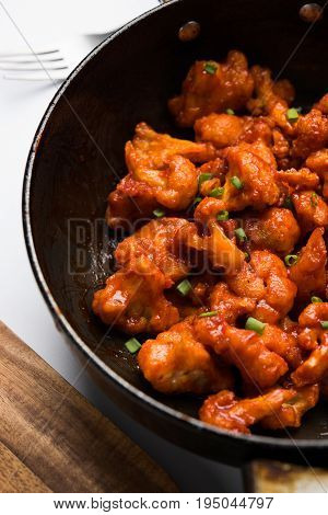 Gobi Manchurian dry - Popular street food of India made of cauliflower florets in a frying pan, selective focus