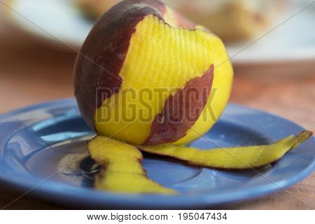 fresh peach peeled on a colored dish
