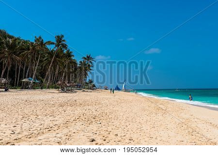 BORACAY WESTERN VISAYAS PHILIPPINES - JANUARY 14 2015: Huge coconut trees tents white sand and green sea composes the beautiful Puka Beach.