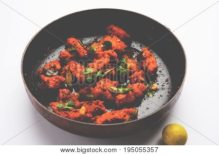 Chicken 65 - spicy deep fried Bar appetizer or quick snack from India in a frying pan over white background, selective focus
