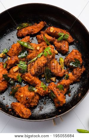 Chicken 65 - spicy deep fried Bar appetizer or quick snack from India in a frying pan over white background, selective focus