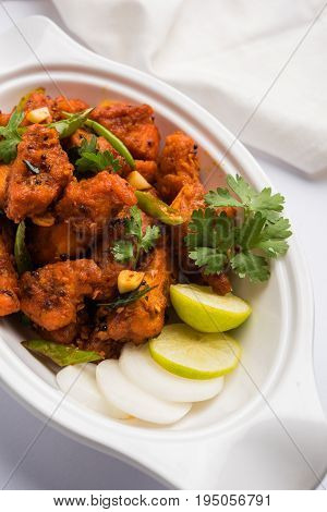 Chicken 65 - spicy deep fried Bar appetizer or quick snack from India in a bowl or plate over white background, selective focus