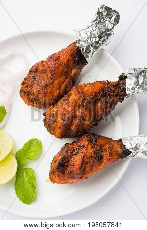Chicken Tangri kabab or kebab - three Chicken leg pieces marinated with red sauce then grilled and served with salad. It can be served with green chutney