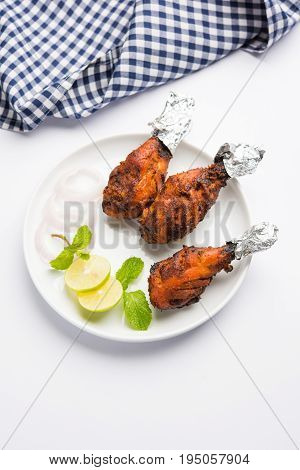 Chicken Tangri kabab or kebab - three Chicken leg pieces marinated with red sauce then grilled and served with salad. It can be served with green chutney